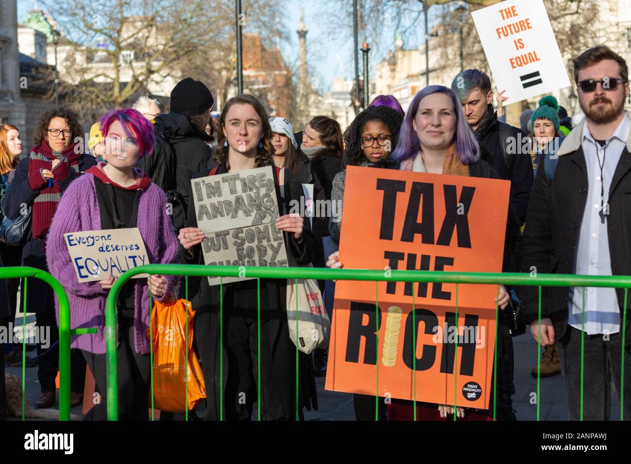 Westminster, Londra, Regno Unito. 18 gennaio 2020. I manifestanti si riuniscono dietro una barricata verde fuori Downing Street, Londra, tenendo cartelli con messaggi come "tutti meritano UGUAGLIANZA", "TASSANO I RICCHI" e "IL FUTURO È UGUALE". La manifestazione richiede un cambiamento sistemico nella distribuzione della ricchezza e nella giustizia sociale. Il clima soleggiato e l'ambiente urbano fanno da cornice alla scena dell'attivismo civico. Una manifestazione e un "momento di caos" di protesta per l'uguaglianza economica a Richmond Terrace, come parte delle proteste globali di Fight Inequality Alliance. Penelope Barritt/Alamy Live News Foto Stock