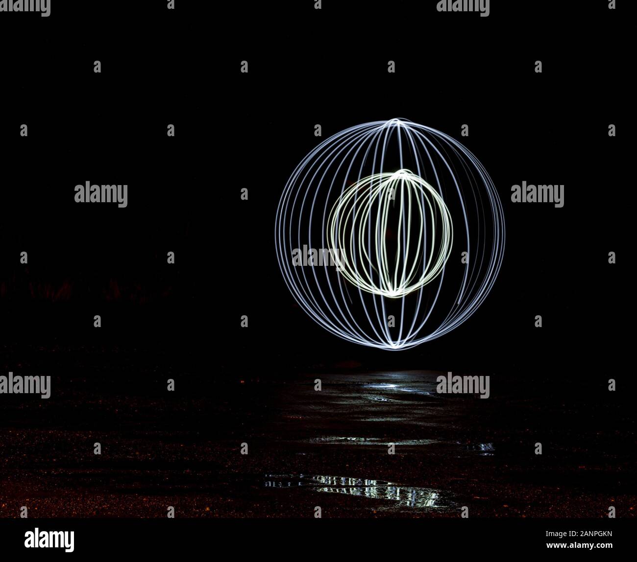 Globo circolare spirali creato da dipingere con la luce nelle tenebre con riflessioni Foto Stock