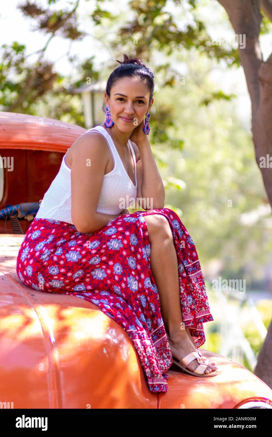 Carino donna latina in posa su una vettura arancione Foto Stock