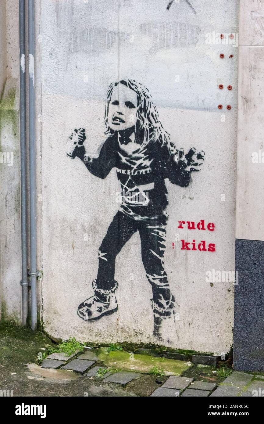 Ragazza giovane con la bomboletta spray wall art graffiti murali e rude kids caption per artista Dotmaster, Williamson Square, Liverpool Foto Stock