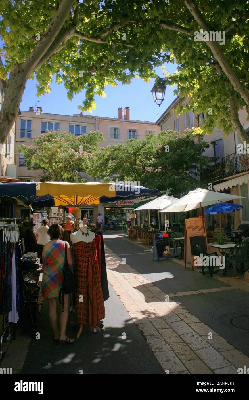 Mercato bancarelle in Place Carnot, Apt, Vaucluse, Provence-Alpes-Côte d'Azur, Francia, con acquirente femminile in primo piano. MODELLO RILASCIATO Foto Stock