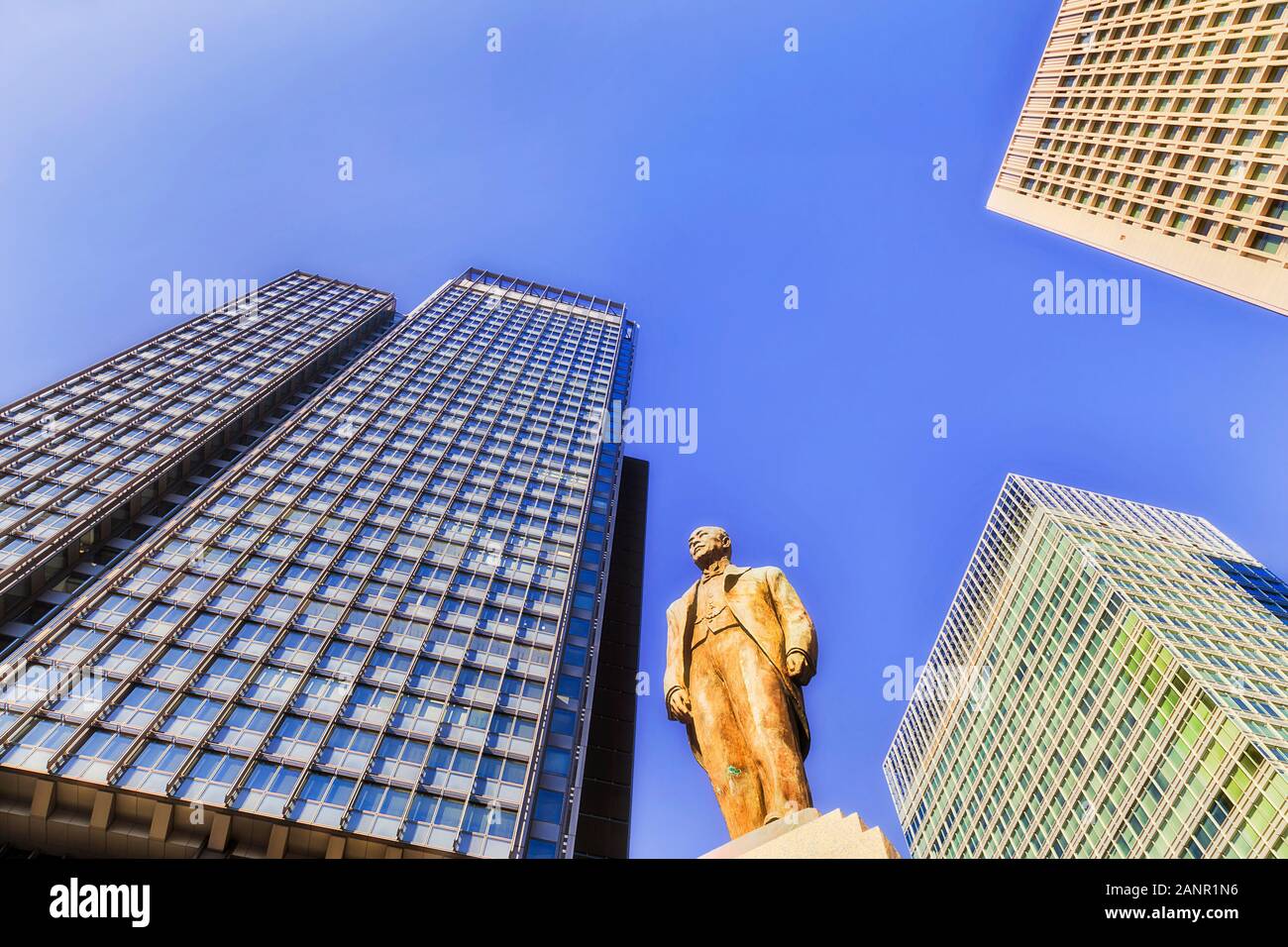 E moderno grattacielo torri contro di cielo blu chiaro in una giornata di sole che circonda il monumento in bronzo di ferrovie giapponesi ingegnere e direttore. Foto Stock