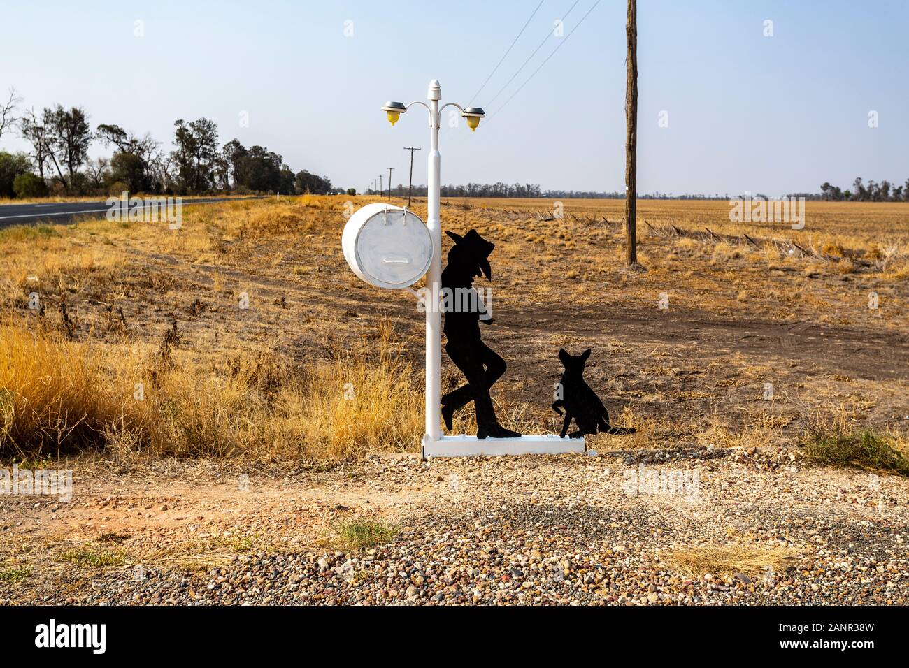 L uomo e il suo cane attesa per la posta su una strada laterale nel NSW, Australia. Esempio di una grande letterbox australiano con un senso dell'umorismo. Foto Stock