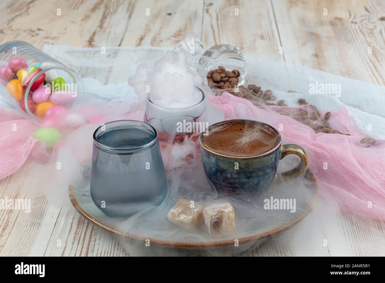 Turca tradizionale caffè nella tazza di porcellana impostare,un bicchiere di acqua e delizie turche e colorati di mandorla caramelle sulla superficie con i chicchi di caffè. Una festa (f Foto Stock
