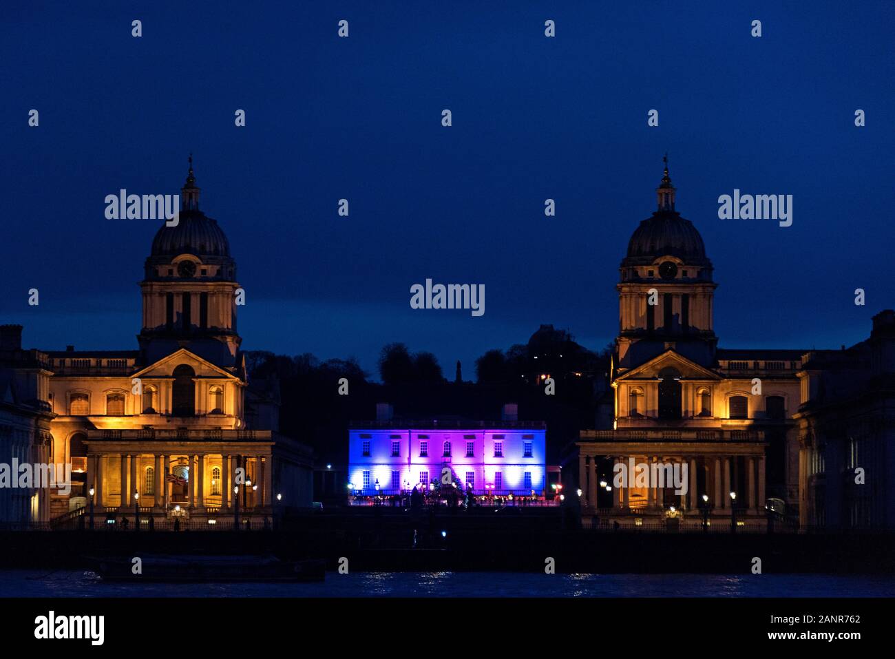 Royal Naval College di Greenwich, fotografato di notte da isola giardini, oltre il Tamigi. La casa della regina è accesa con rosa e viola. London, E Foto Stock
