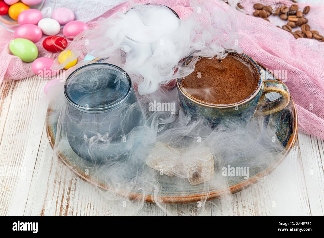 Turca tradizionale caffè nella tazza di porcellana impostare,un bicchiere di acqua e delizie turche e colorati di mandorla caramelle sulla superficie con i chicchi di caffè. Una festa (f Foto Stock