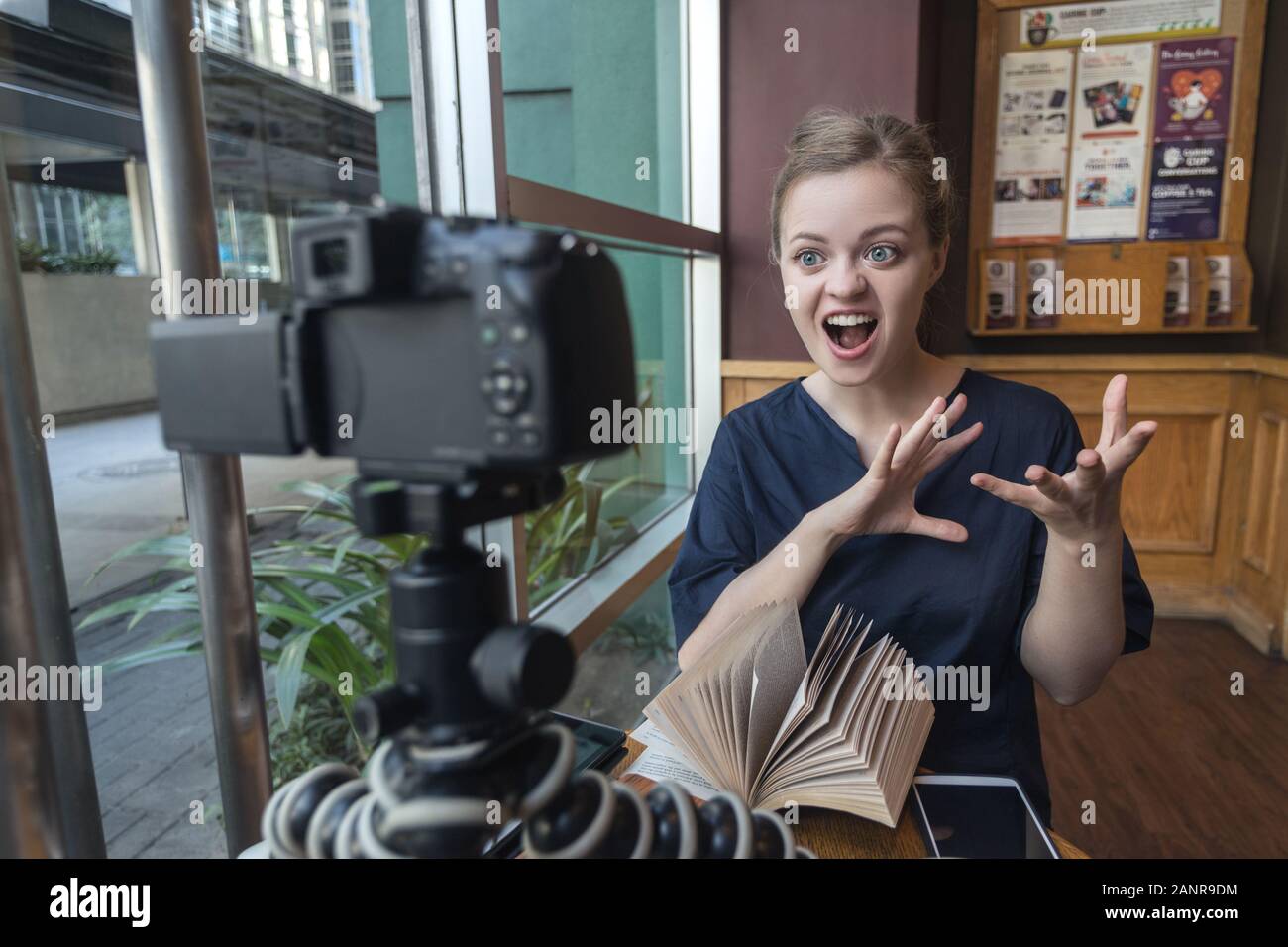 Sorridente giovane donna caucasica ragazza facendo un video blog (vlog) con la macchina fotografica in un caffè Foto Stock
