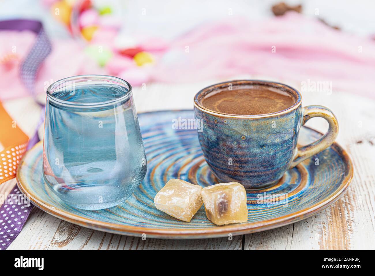 Turca tradizionale caffè nella tazza di porcellana impostare,un bicchiere di acqua e delizie turche e colorati di mandorla caramelle sulla superficie con i chicchi di caffè. Una festa (f Foto Stock
