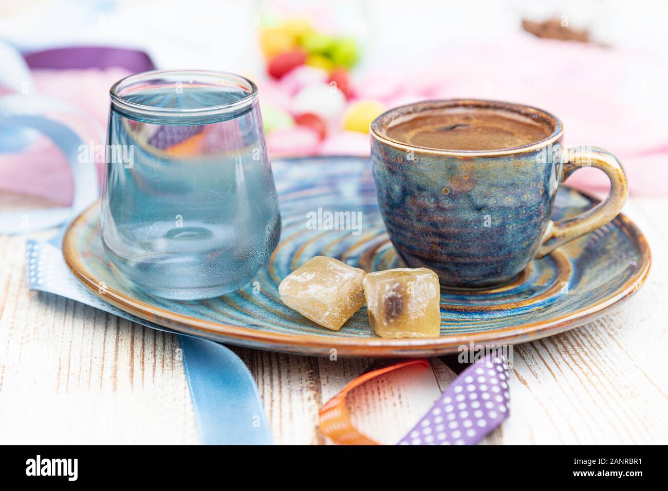 Turca tradizionale caffè nella tazza di porcellana impostare,un bicchiere di acqua e delizie turche e colorati di mandorla caramelle sulla superficie con i chicchi di caffè. Una festa (f Foto Stock