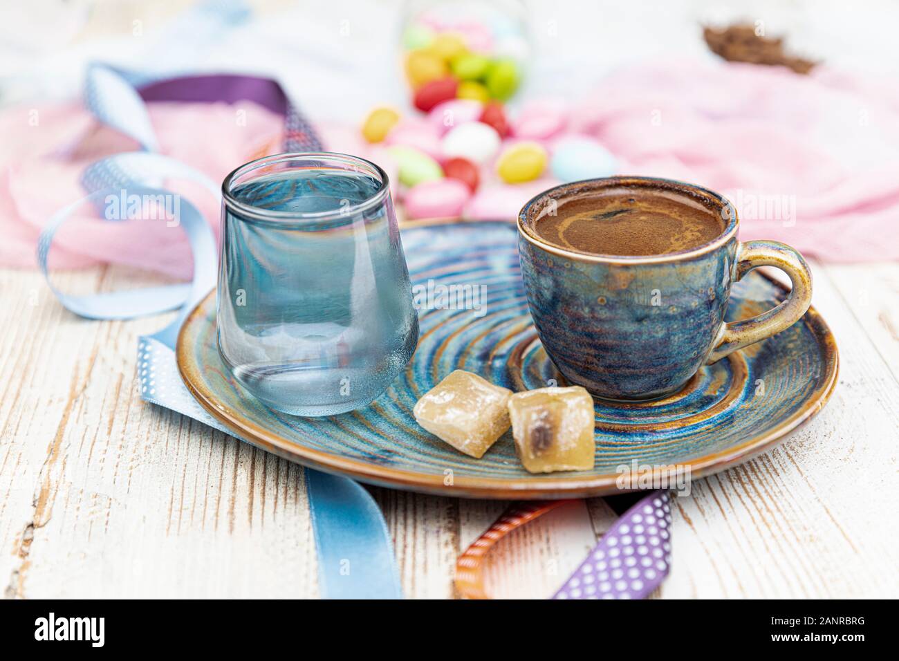 Turca tradizionale caffè nella tazza di porcellana impostare,un bicchiere di acqua e delizie turche e colorati di mandorla caramelle sulla superficie con i chicchi di caffè. Una festa (f Foto Stock