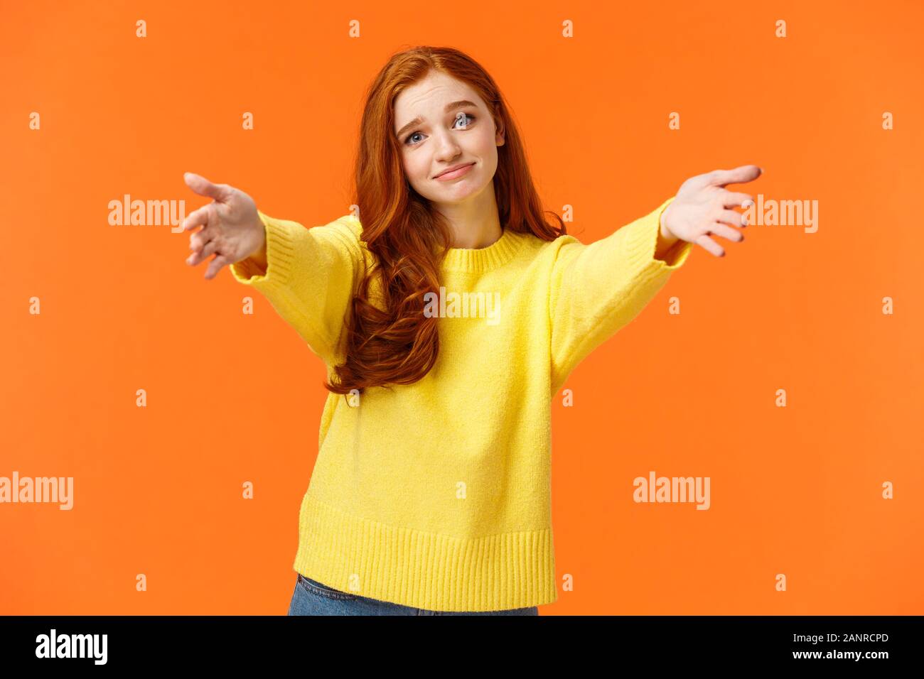 Ragazza chiedendo a venire qui a dare Cheer up abbraccio. Carino e toccò la gara redhead donna in felpa gialla, estendono bracci,allungare le mani avanti per coccolare Foto Stock