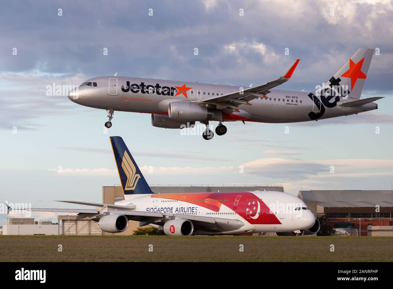Jetstar Airways Airbus A320 circa di atterrare all'Aeroporto di Melbourne mentre un Singapore Airlines Airbus A380 attende di decollo. Foto Stock