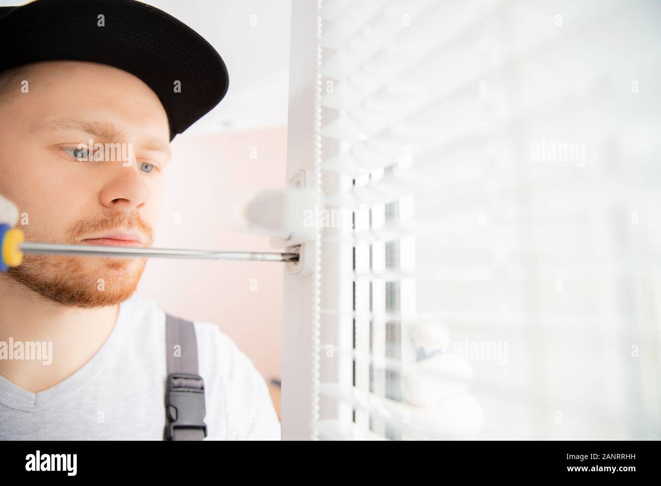 Operaio edile uomo utilizza un cacciavite a manico a vite di plastica di installazione UPVC bianco windows in casa Foto Stock