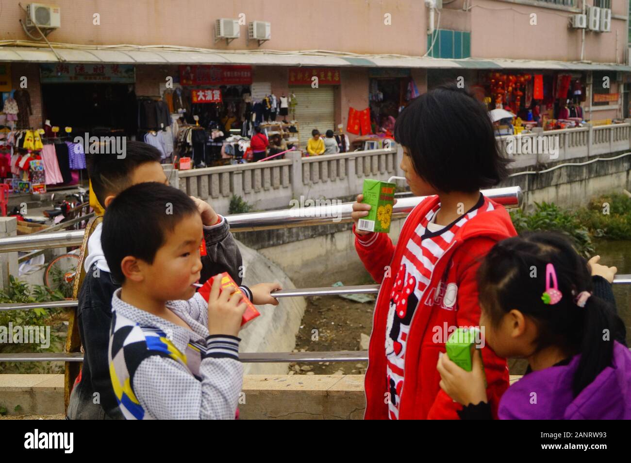 Studenti della scuola primaria che hanno le vacanze invernali giocare nelle strade e bere un drink. In Shenzhen, Cina. Foto Stock