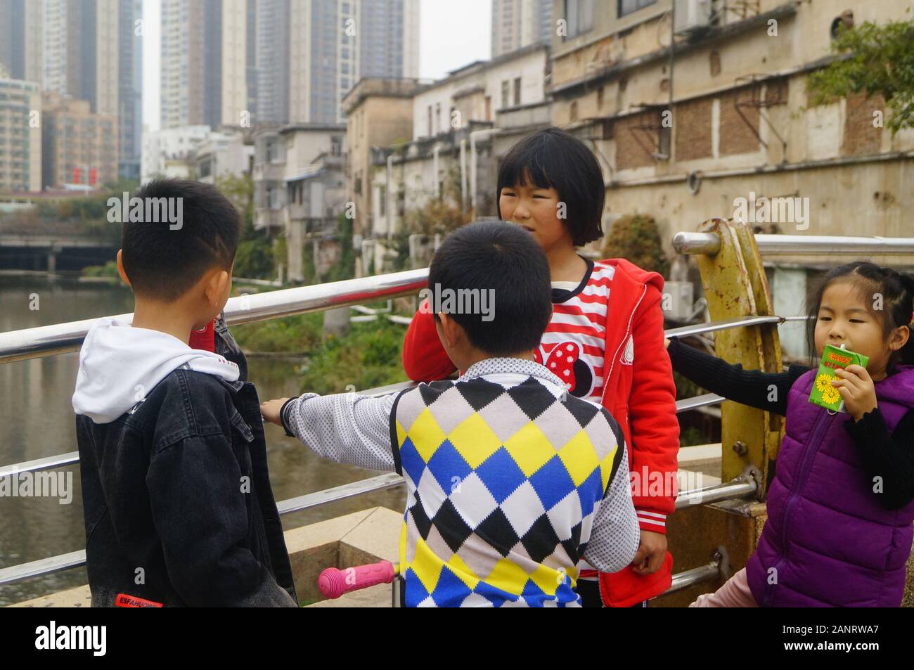 Studenti della scuola primaria che hanno le vacanze invernali giocare nelle strade e bere un drink. In Shenzhen, Cina. Foto Stock