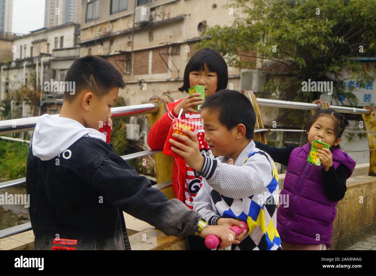 Studenti della scuola primaria che hanno le vacanze invernali giocare nelle strade e bere un drink. In Shenzhen, Cina. Foto Stock
