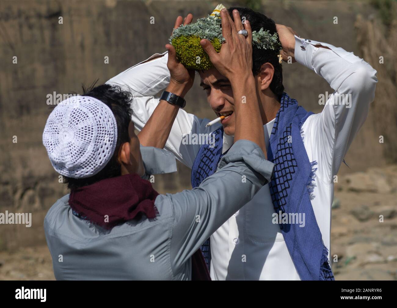 Ritratto di un fiore uomo regolazione di una corona di fiori sulla testa, Jizan provincia, Addayer, Arabia Saudita Foto Stock