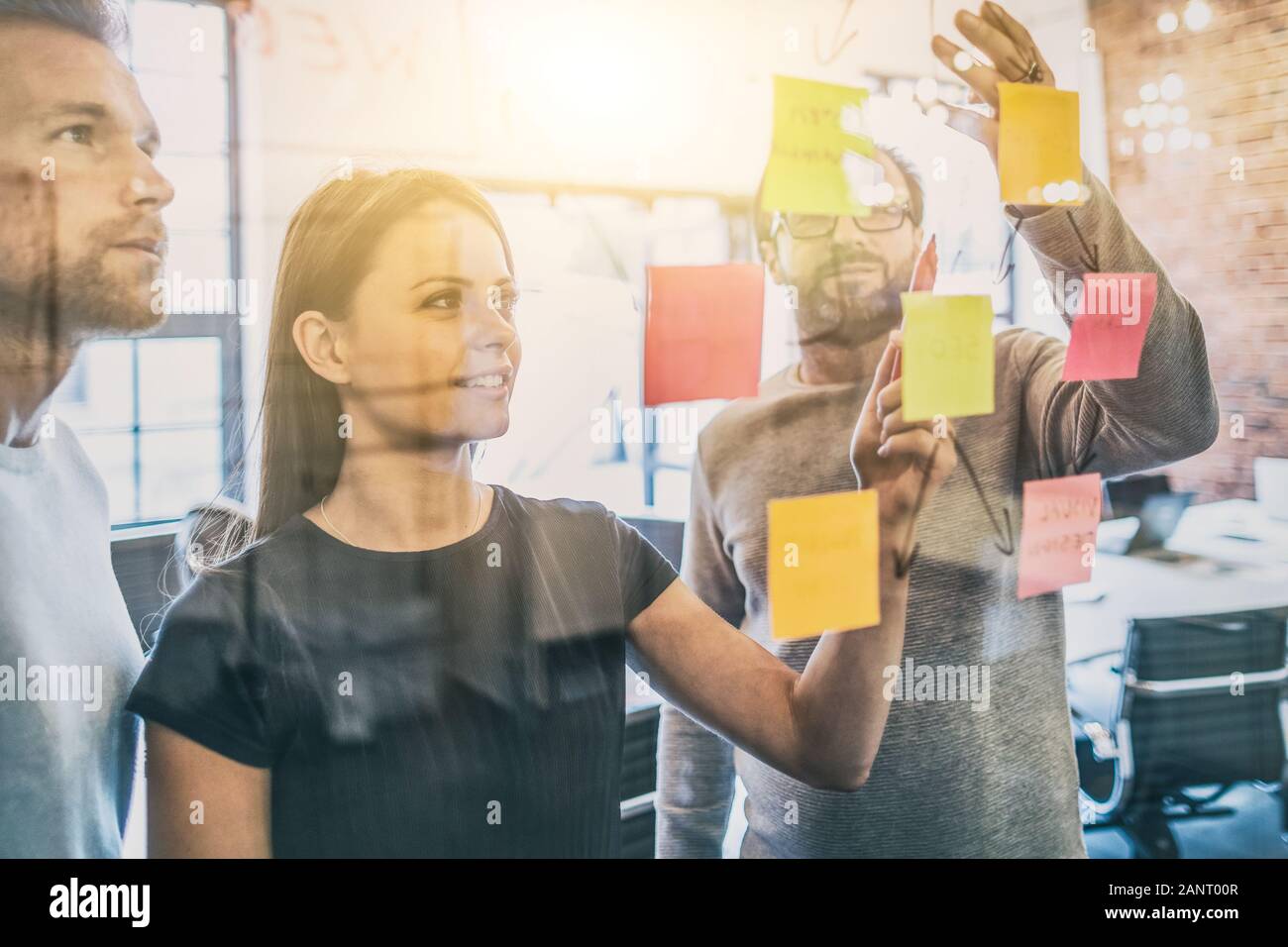 La gente di affari riunione in ufficio e uso di post-it per condividere idea. Concetto di brainstorming. Nota adesiva sulla parete di vetro. Foto Stock