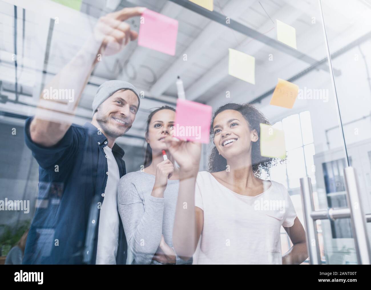 La gente di affari riunione in ufficio e uso di post-it per condividere idea. Concetto di brainstorming. Nota adesiva sulla parete di vetro. Foto Stock