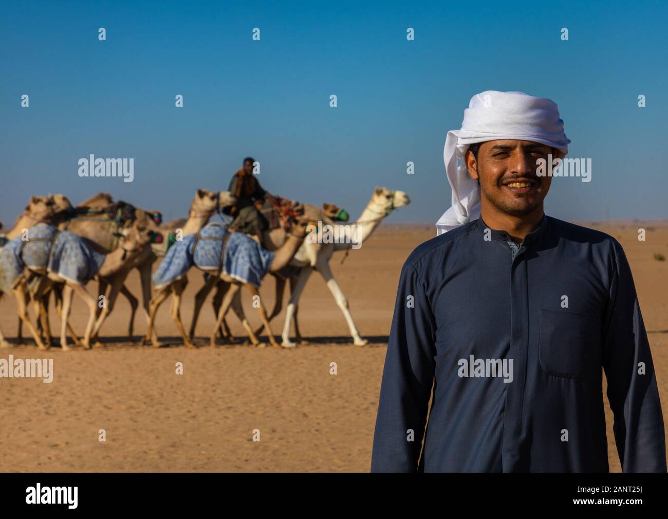 Arabia uomo davanti di cammelli per la formazione in gara il Rub' al Khali desert, provincia di Najran, Hubuna, Arabia Saudita Foto Stock