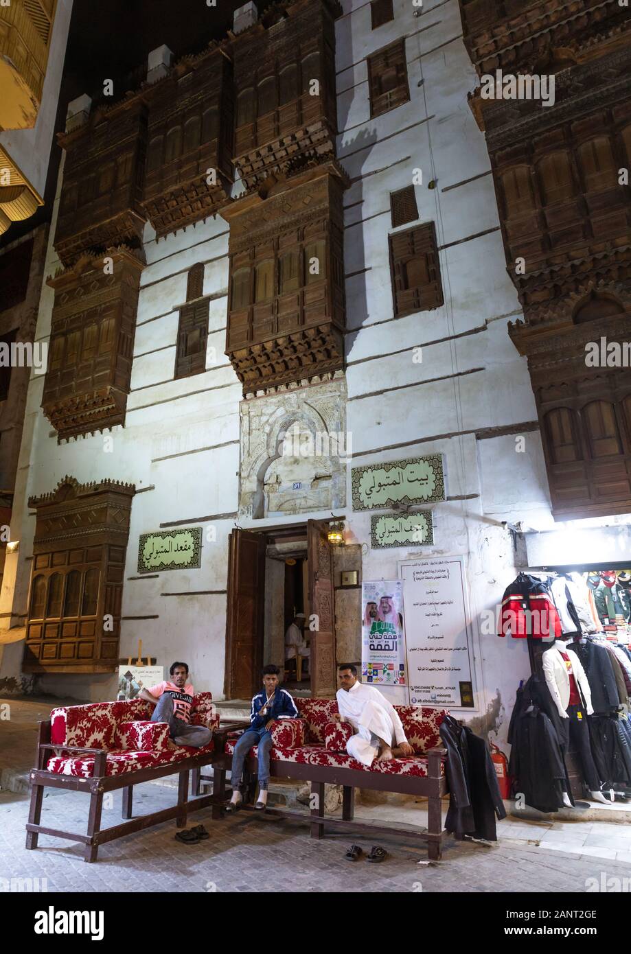 Gli uomini in appoggio su letti di fronte a una casa storica con mashrabiyas in legno di al-Balad, Mecca provincia, Jeddah, Arabia Saudita Foto Stock