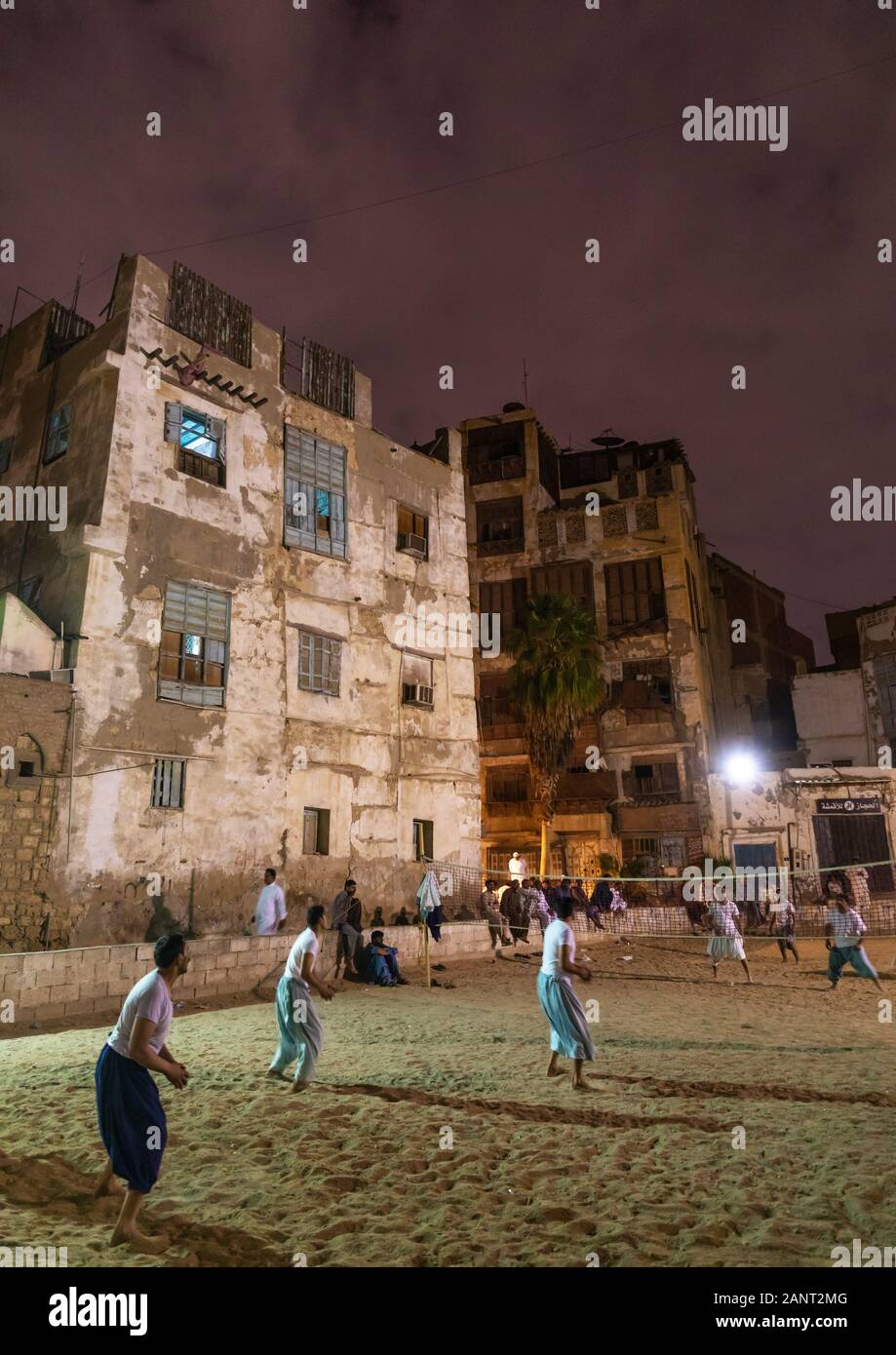 Gli uomini la riproduzione di beach volley di fronte vecchie case con mashrabiyas di al-Balad trimestre, Mecca provincia, Jeddah, Arabia Saudita Foto Stock
