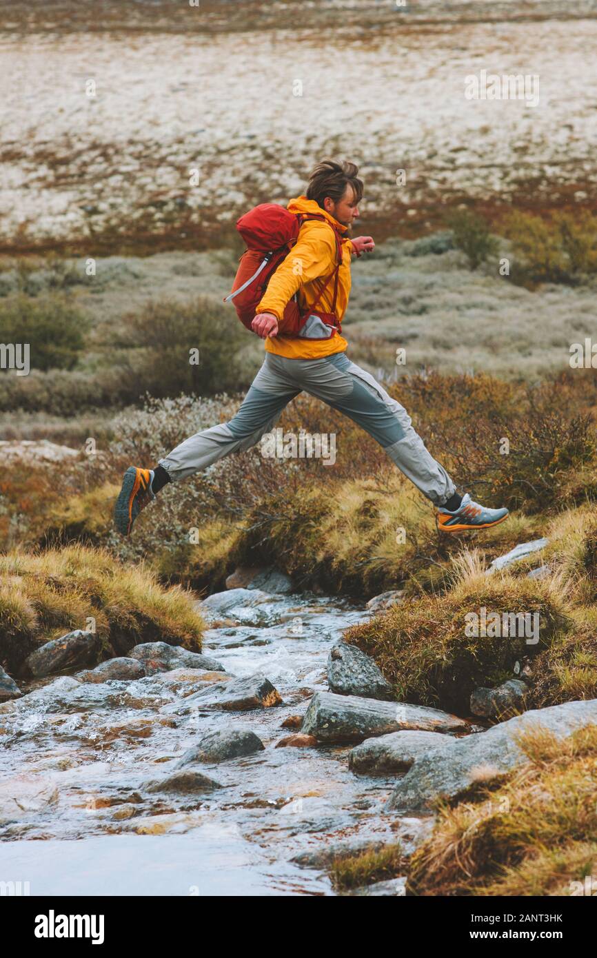 L'uomo escursionista saltando su fiume viaggi avventura trekking vacanza attiva uno stile di vita sano outdoor in Norvegia Foto Stock