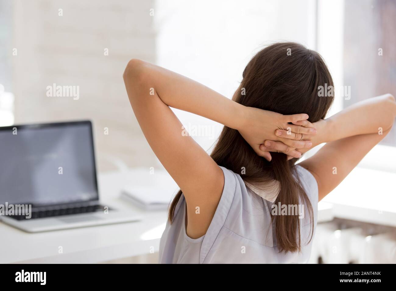 Vista posteriore femmina mettendo le mani dietro la testa appoggiata su una sedia Foto Stock