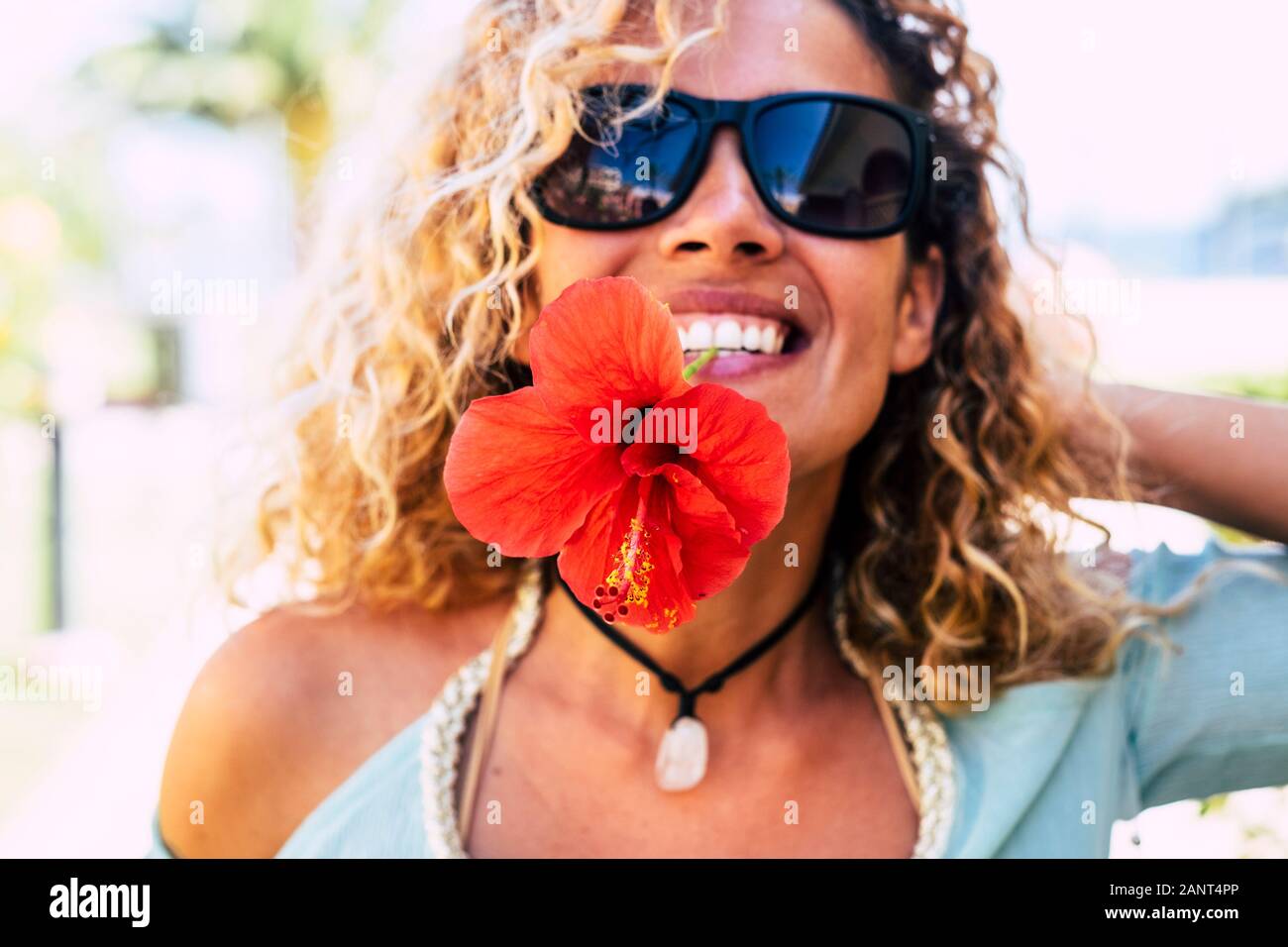 La molla e il concetto di felicità con felice allegro lady prendendo un grande fiore rosso con i denti in bocca sorridente e giocare nella parte anteriore della telecamera - bea Foto Stock