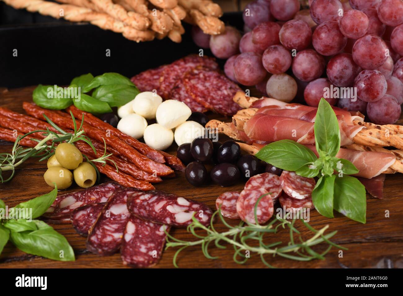 Antipasto. Piatto con salsicce, prosciutto, salame, croccanti grissini con uve. Un antipasto a base di carne è una grande idea Foto Stock