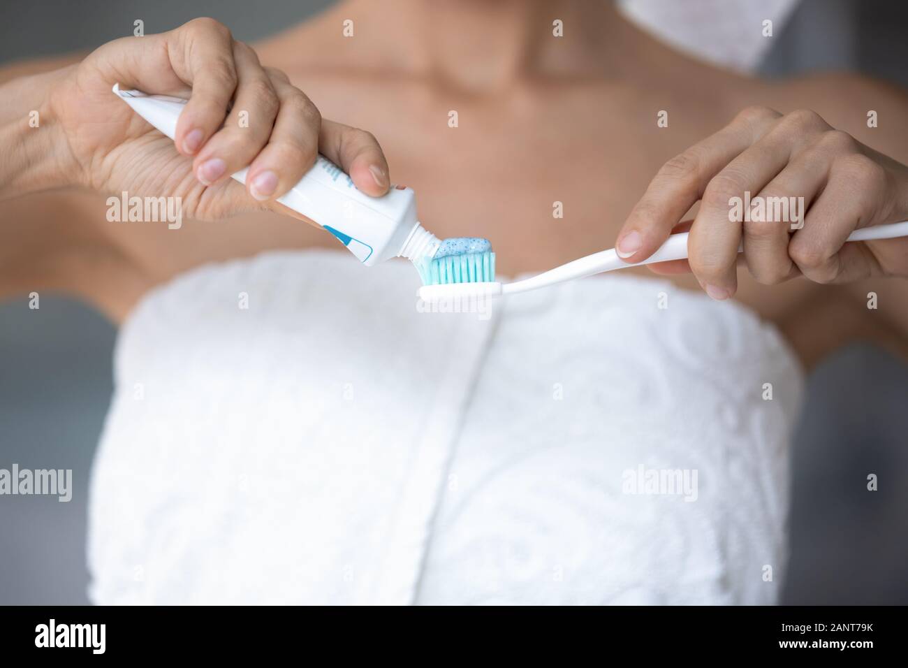 Close up donna avvolta in asciugamano applicando una pasta dentifricia su uno spazzolino da denti Foto Stock