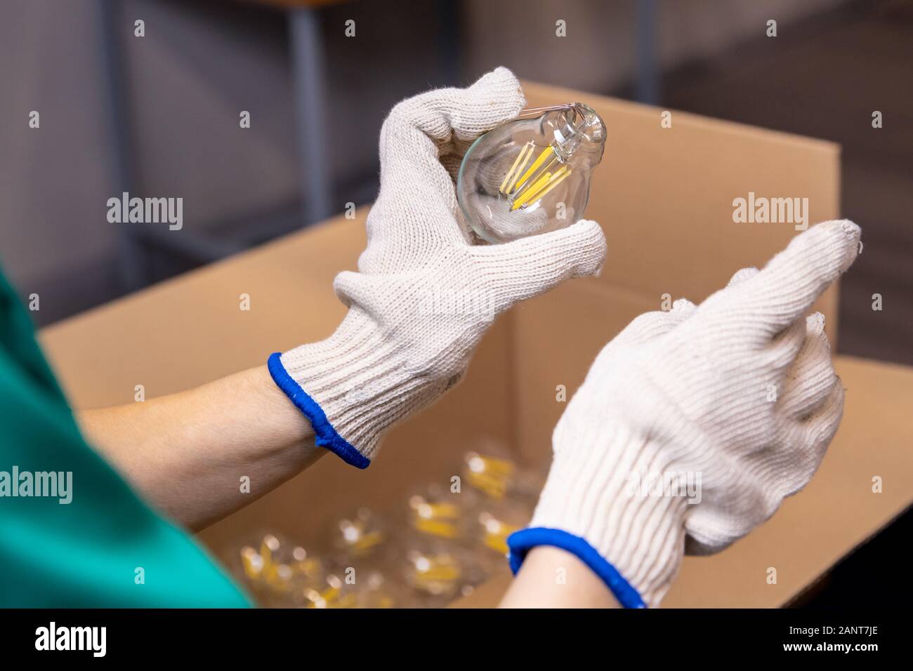 Lavoratore mani preleva il vetro elettrico lampada, posizionare il coperchio sui fili Foto Stock