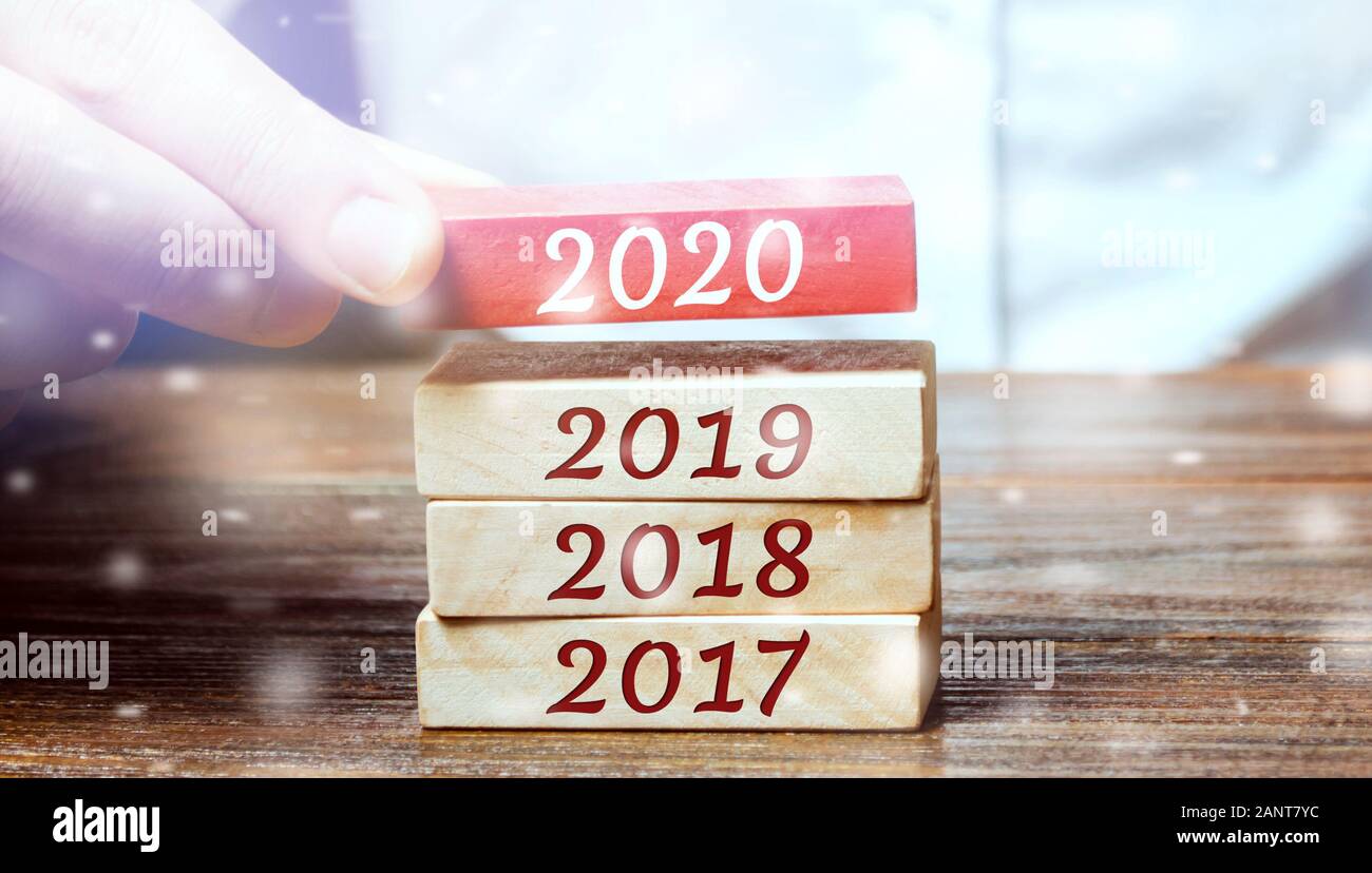 Imprenditore costruisce i blocchi di legno 2020. Il concetto di inizio del nuovo anno. Nuovi obiettivi. Il prossimo decennio. Le tendenze e i cambiamenti nel mondo. Costruire pl Foto Stock