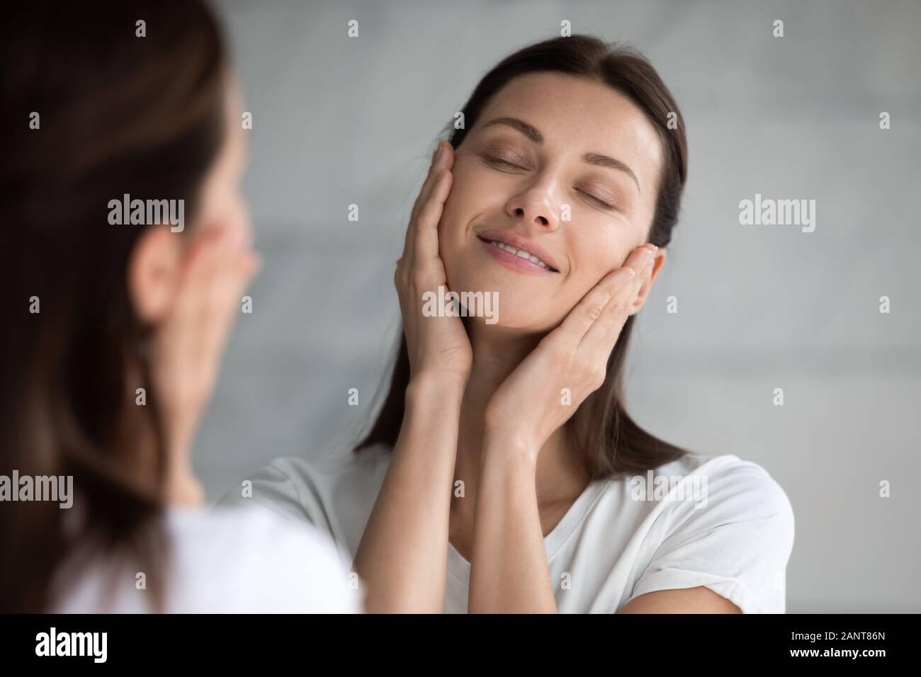 Close up sorridente giovane donna godendo, toccando liscia pelle perfetta Foto Stock