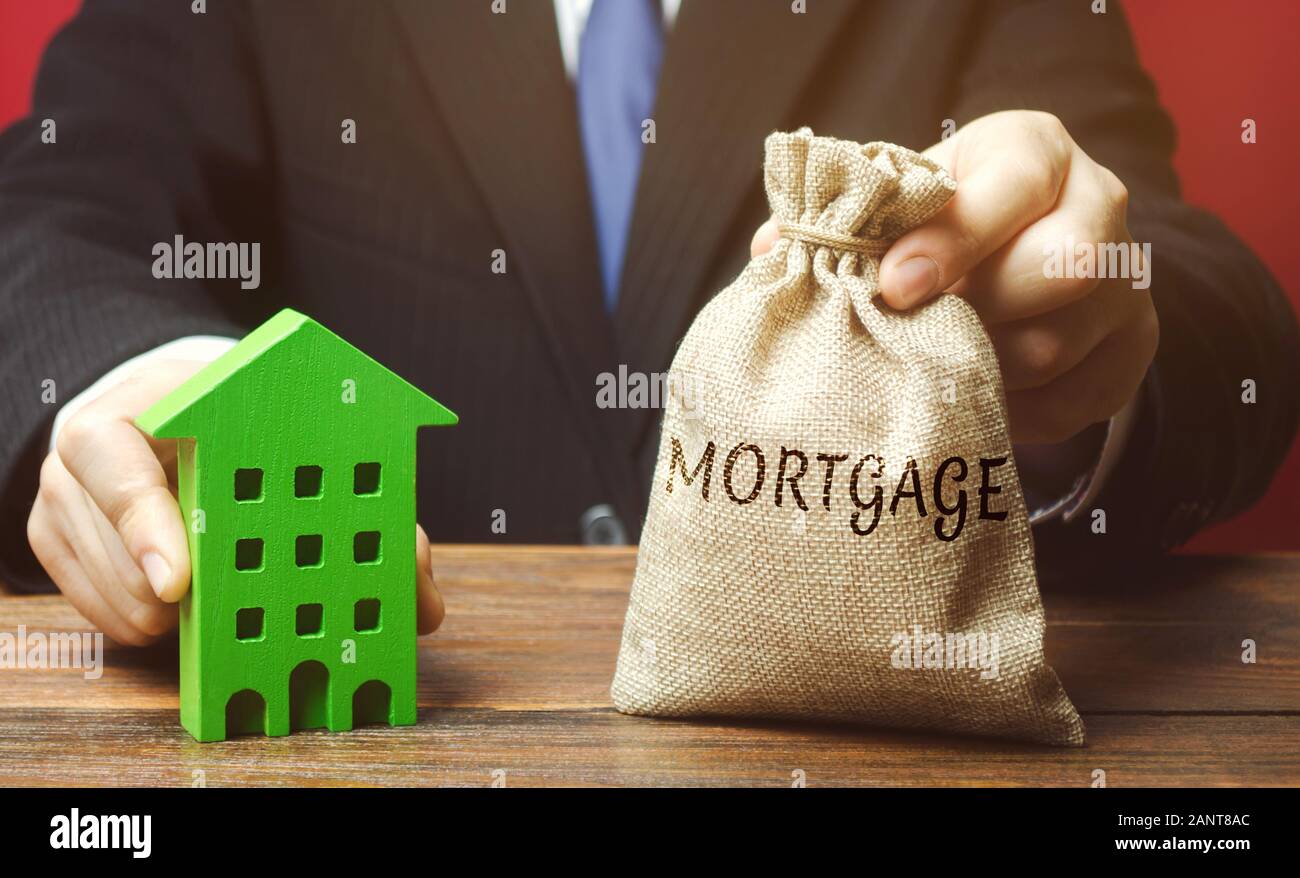 Imprenditore detiene un sacco di denaro con la parola mutuo e una casa di legno. Immobiliare di concetto. Prestito per appartamento e l'alloggiamento. Assicurazione del credito. Busine Foto Stock