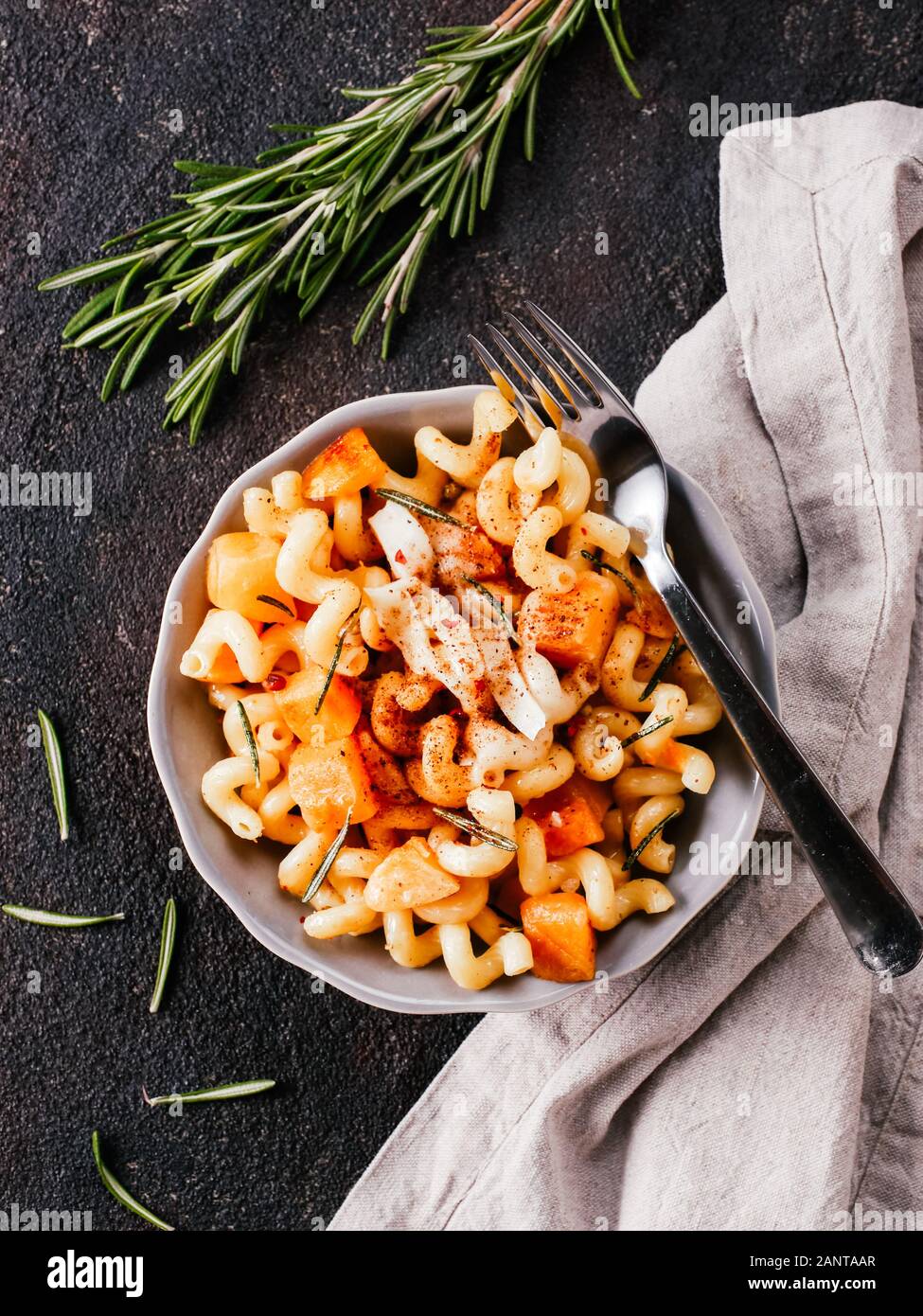 Fusilli con zucca, rosmarino e formaggio brie. Idea ricetta pasta. Cibo vegetariano. Pasta fatta in casa piatto in ciotola grigio nero su sfondo di calcestruzzo. Copia dello spazio. Vista superiore piatta o laici. Foto Stock