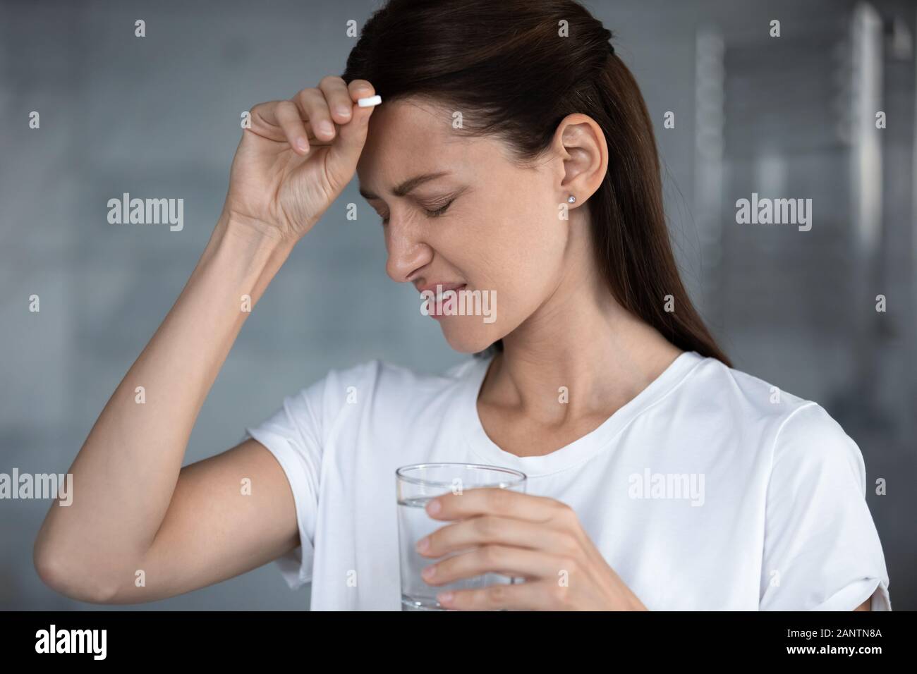 Malati donna infelice che soffrono di mal di testa, tenendo la pillola, toccando la fronte Foto Stock