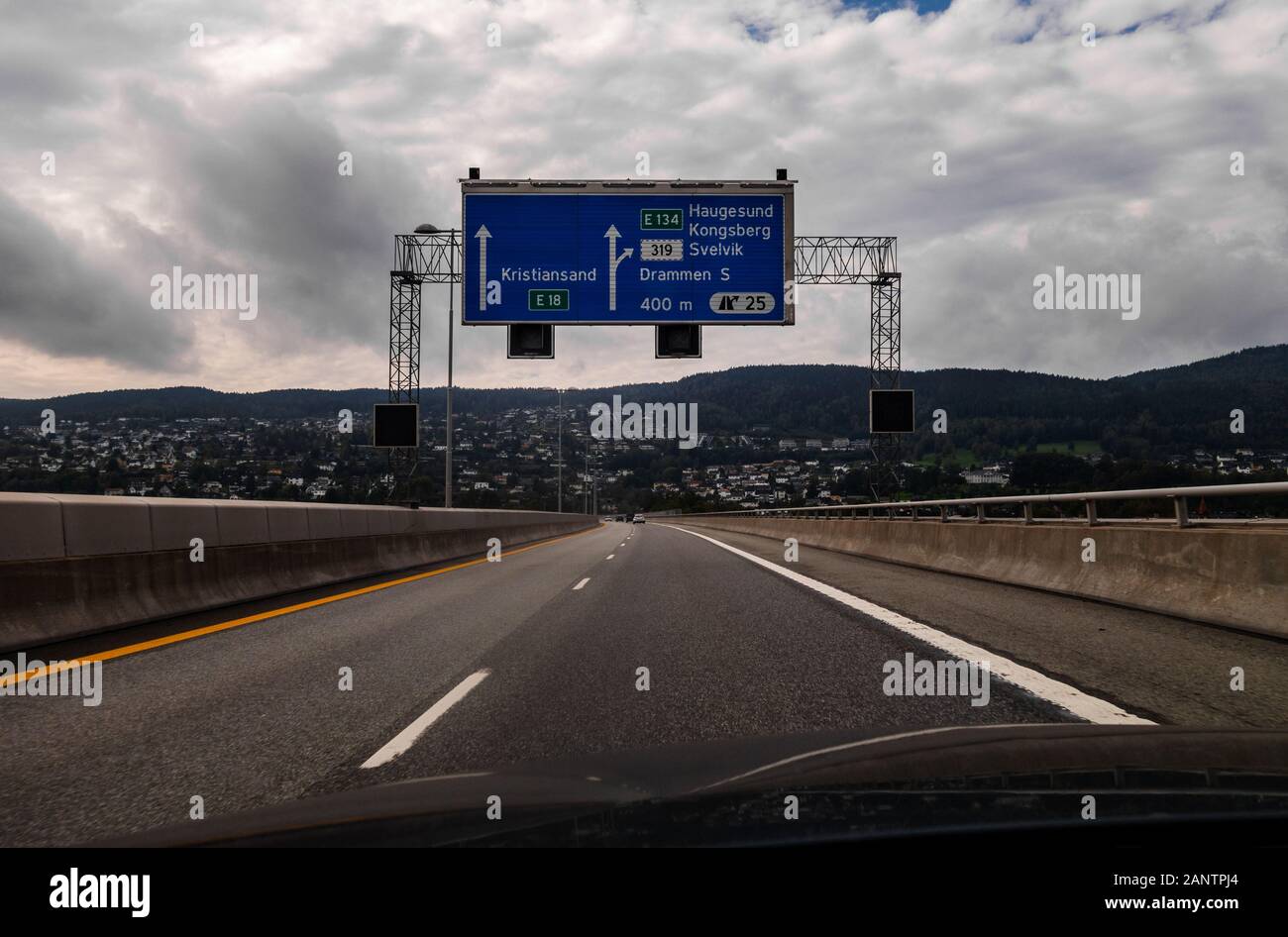 Drammen Norvegia Vista dall'autostrada della città che con gli edifici lungo il crinale con un cartello sopra la strada Foto Stock