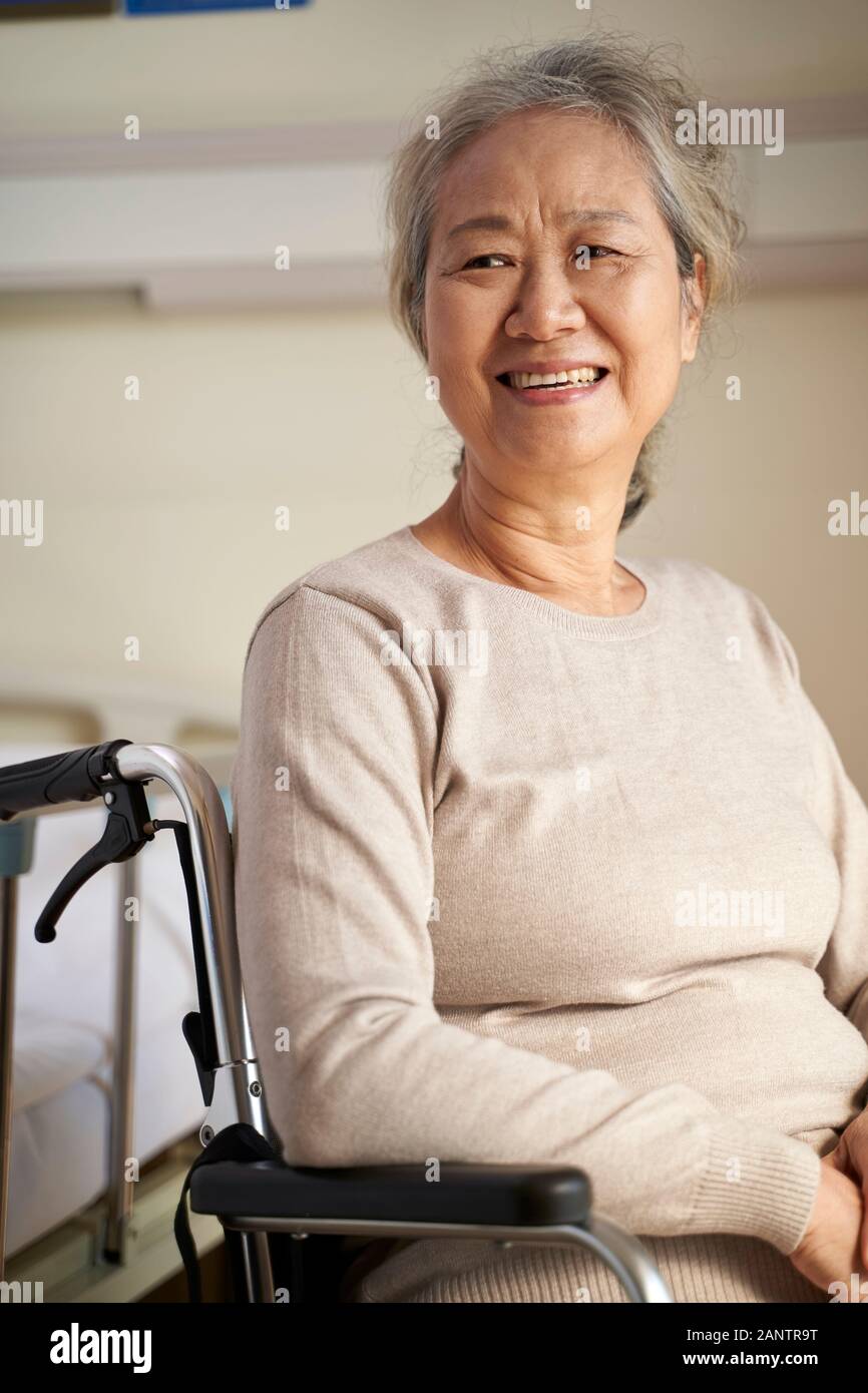 Felice senior donna asiatica seduto nella sedia a rotelle nella sua stanza nella casa di cura, felice e sorridente Foto Stock