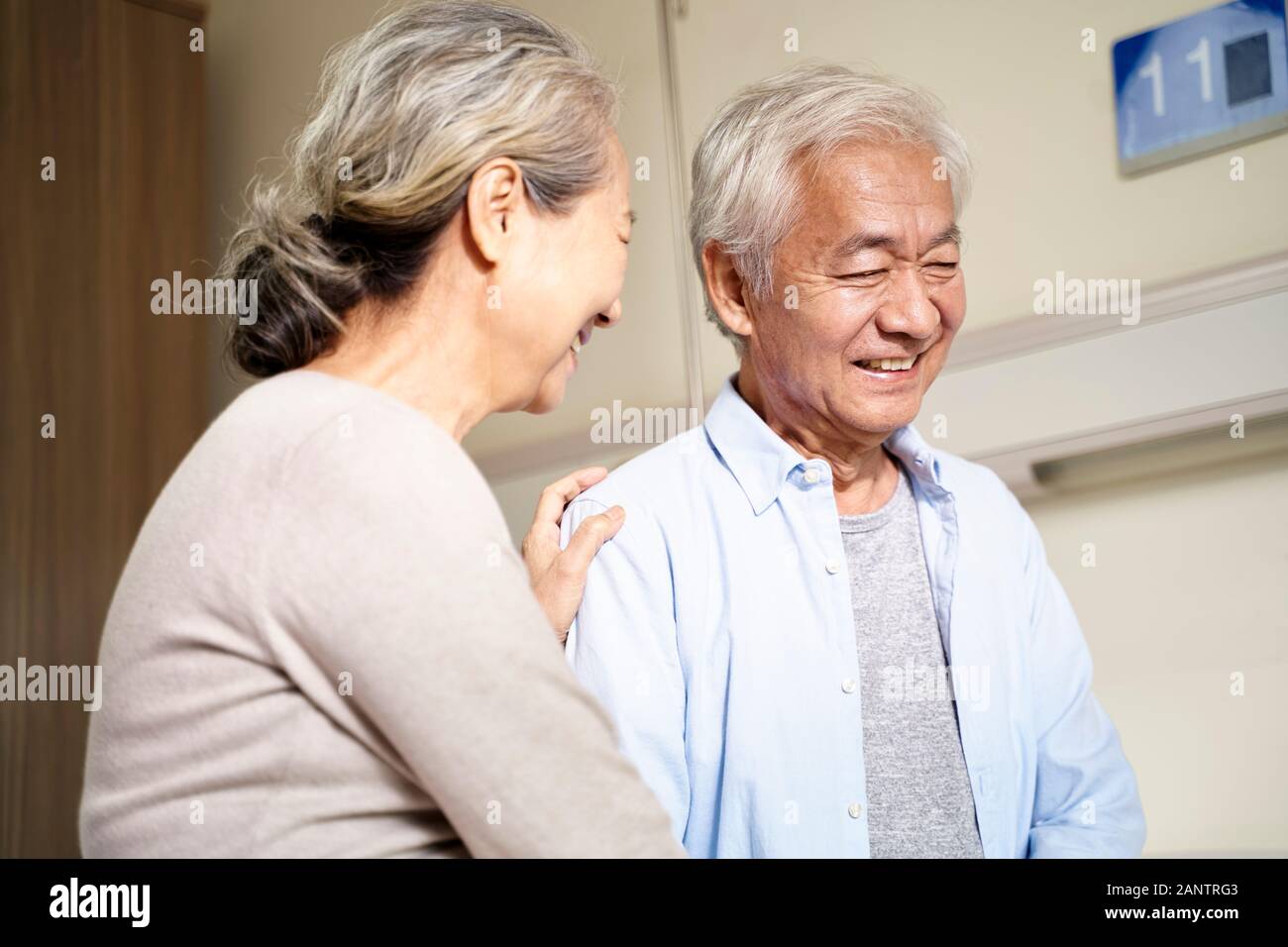 Felice asian coppia senior parlando in ospedale Foto Stock