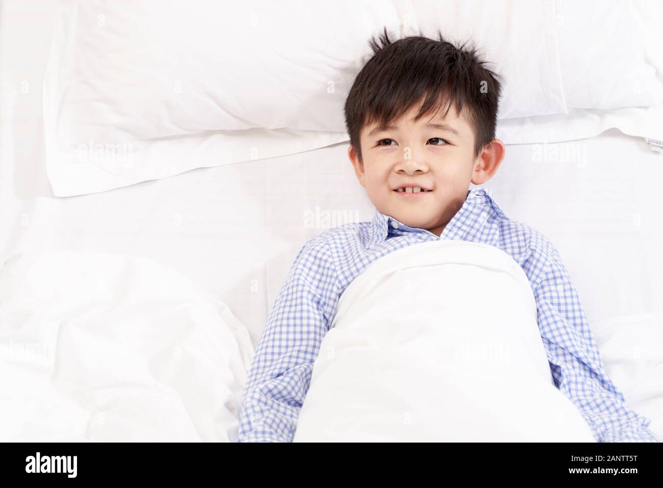 5 anno di età bambino giacente in letto di ospedale cercando felice Foto Stock