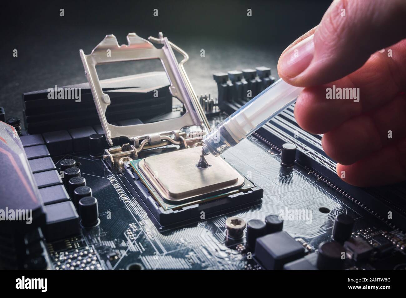 Primo piano per il tecnico che preme o applica il composto di pasta termica sulla parte superiore della cpu principale nel socket. Concetto di riparazione o aggiornamento Foto Stock