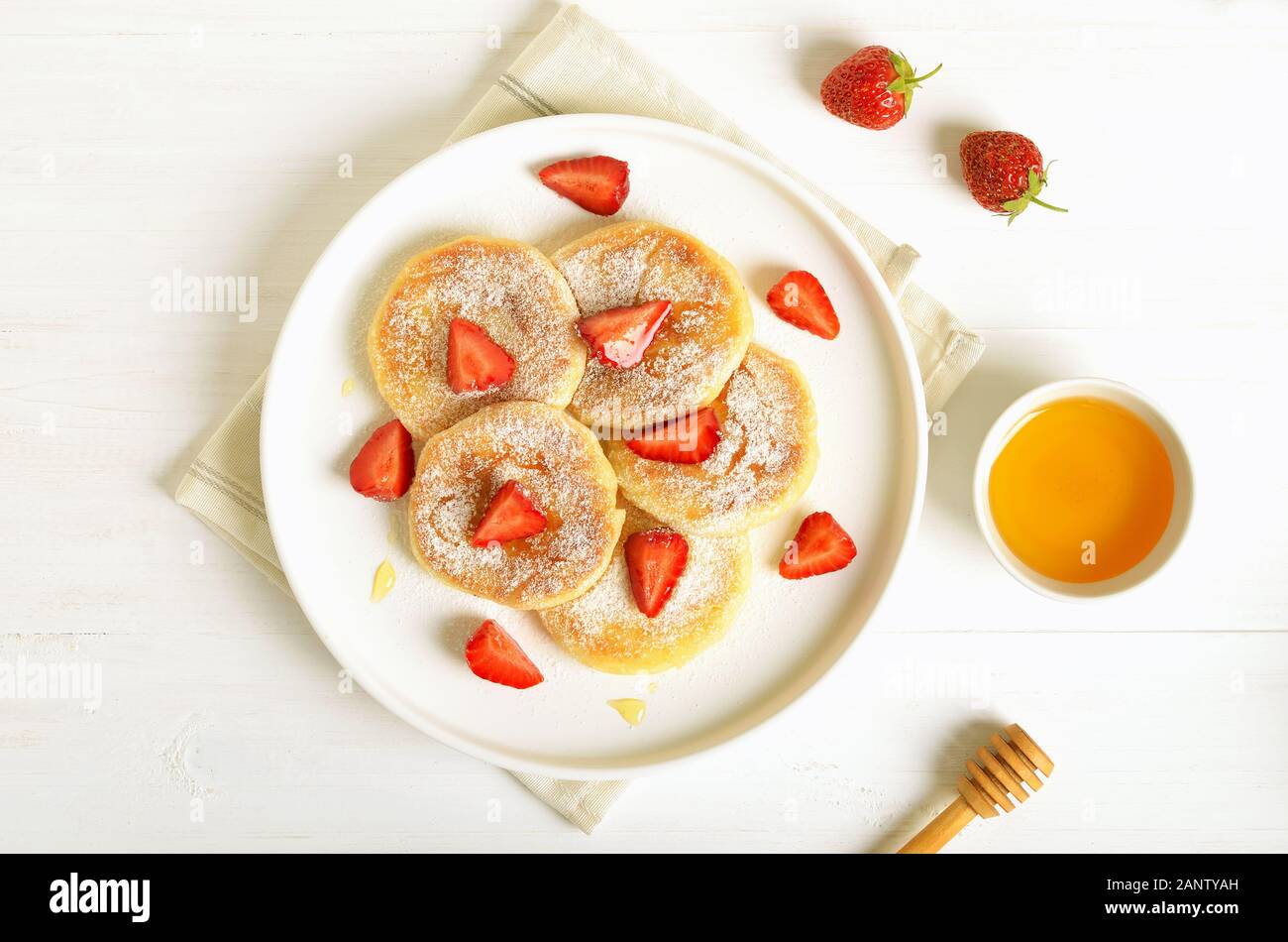 Pancake fatti in casa con ricotta e fragole fette. Vista superiore, piatto laici. Una sana prima colazione Foto Stock