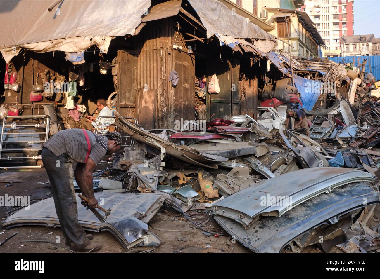 Un operaio che prende le parti delle vecchie automobili smantellate al mercato dei ladri (Chor Bazar) a Mumbai, India, qualche cosa riutilizzabile essere venduto Foto Stock