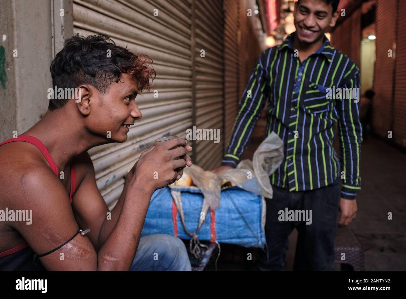 Due allegri giovani migranti provenienti da Uttar Pradesh (India settentrionale) nel mercato di Crawford, Mumbai, India, uno che ha il suo tè al mattino presto Foto Stock