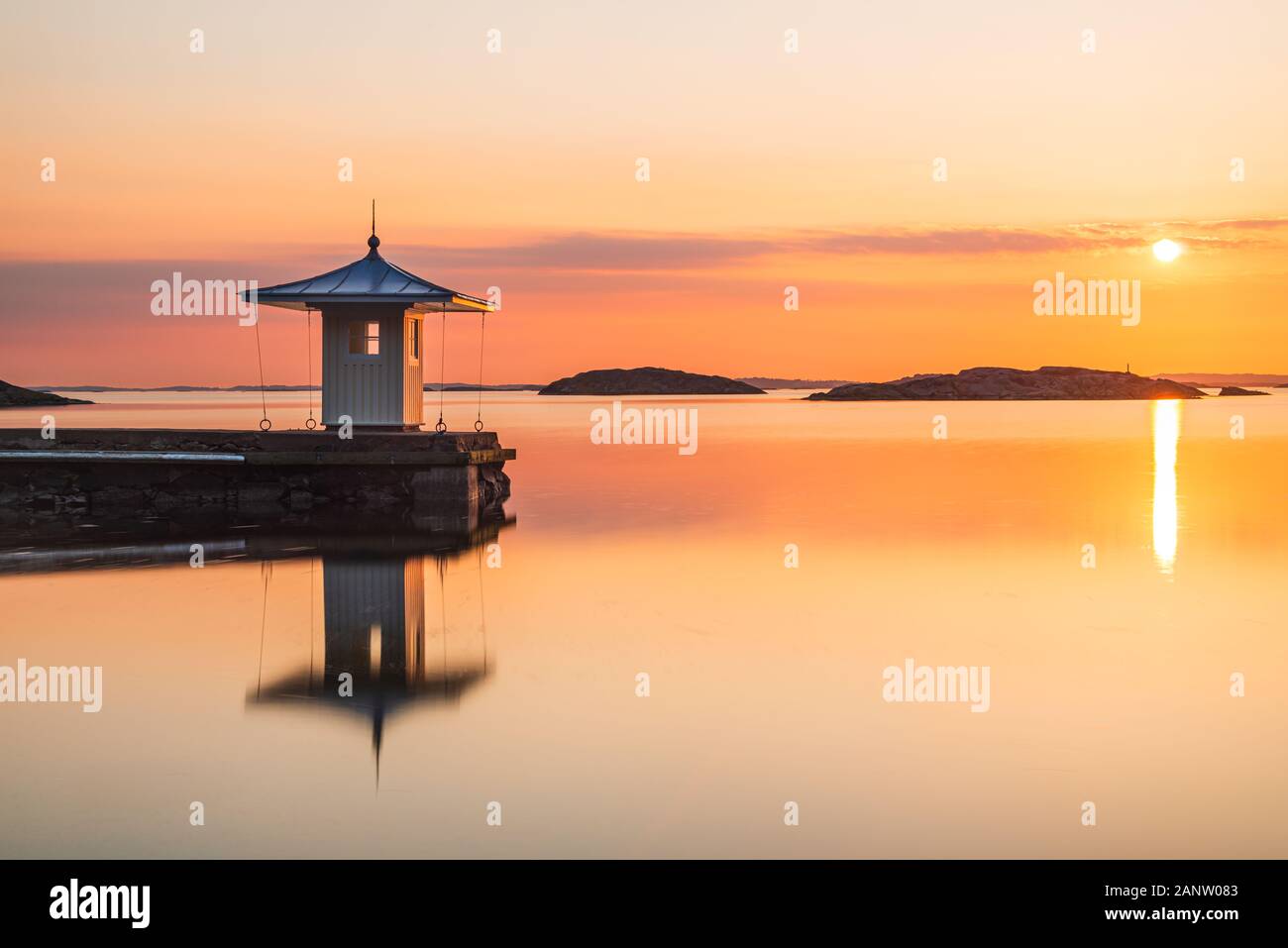 La riflessione del molo sul mare idilliaco durante il tramonto Foto Stock