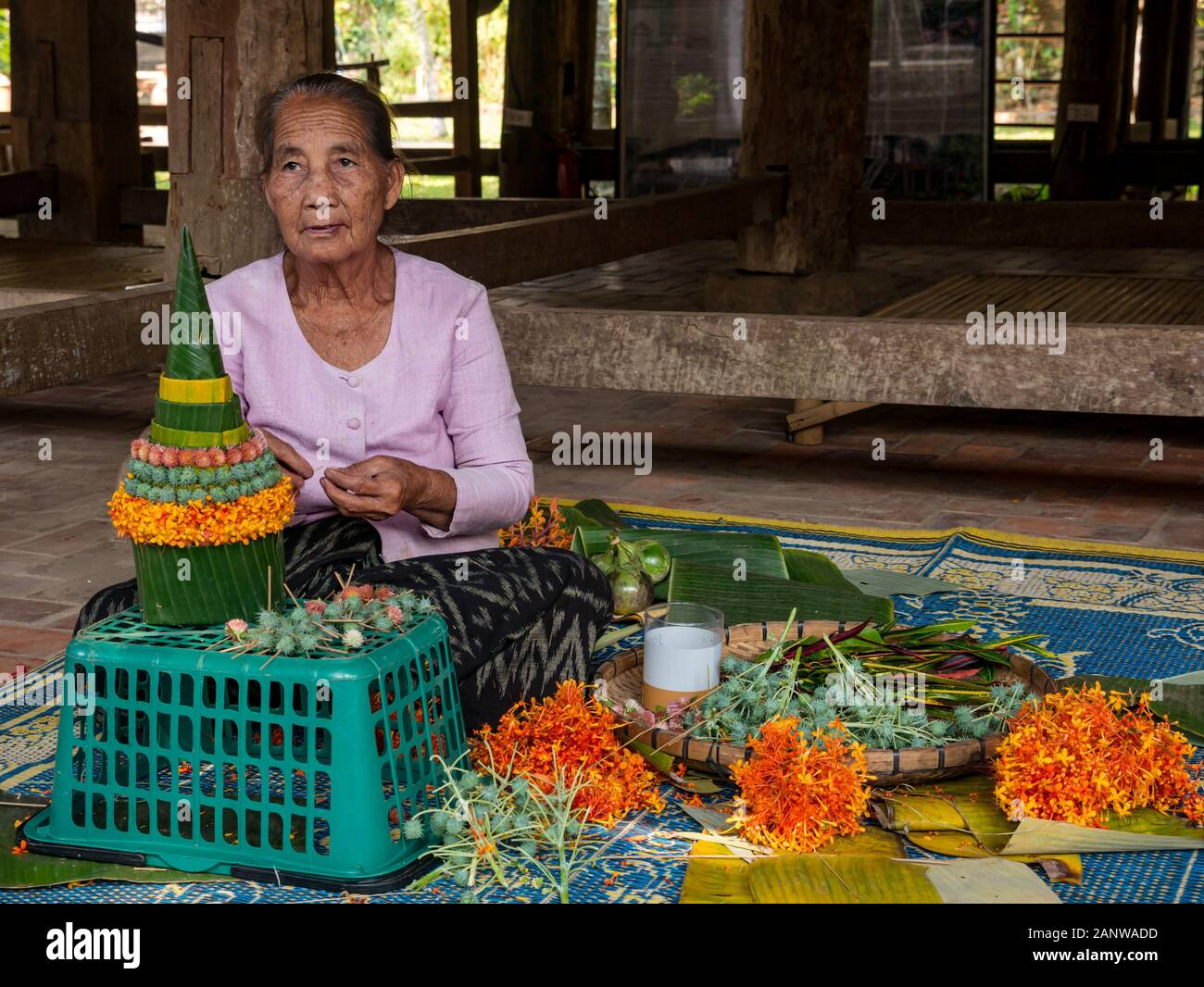 Vecchia donna rendendo religioso sacrificale festival offre decorazioni, Luang Prabang, Laos, sud-est asiatico Foto Stock