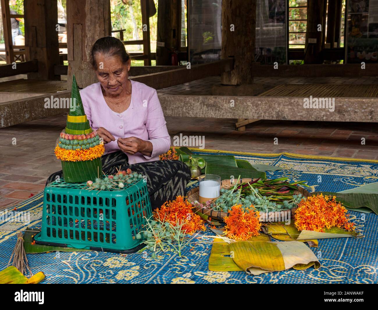 Vecchia donna rendendo religioso sacrificale festival offre decorazioni, Luang Prabang, Laos, sud-est asiatico Foto Stock