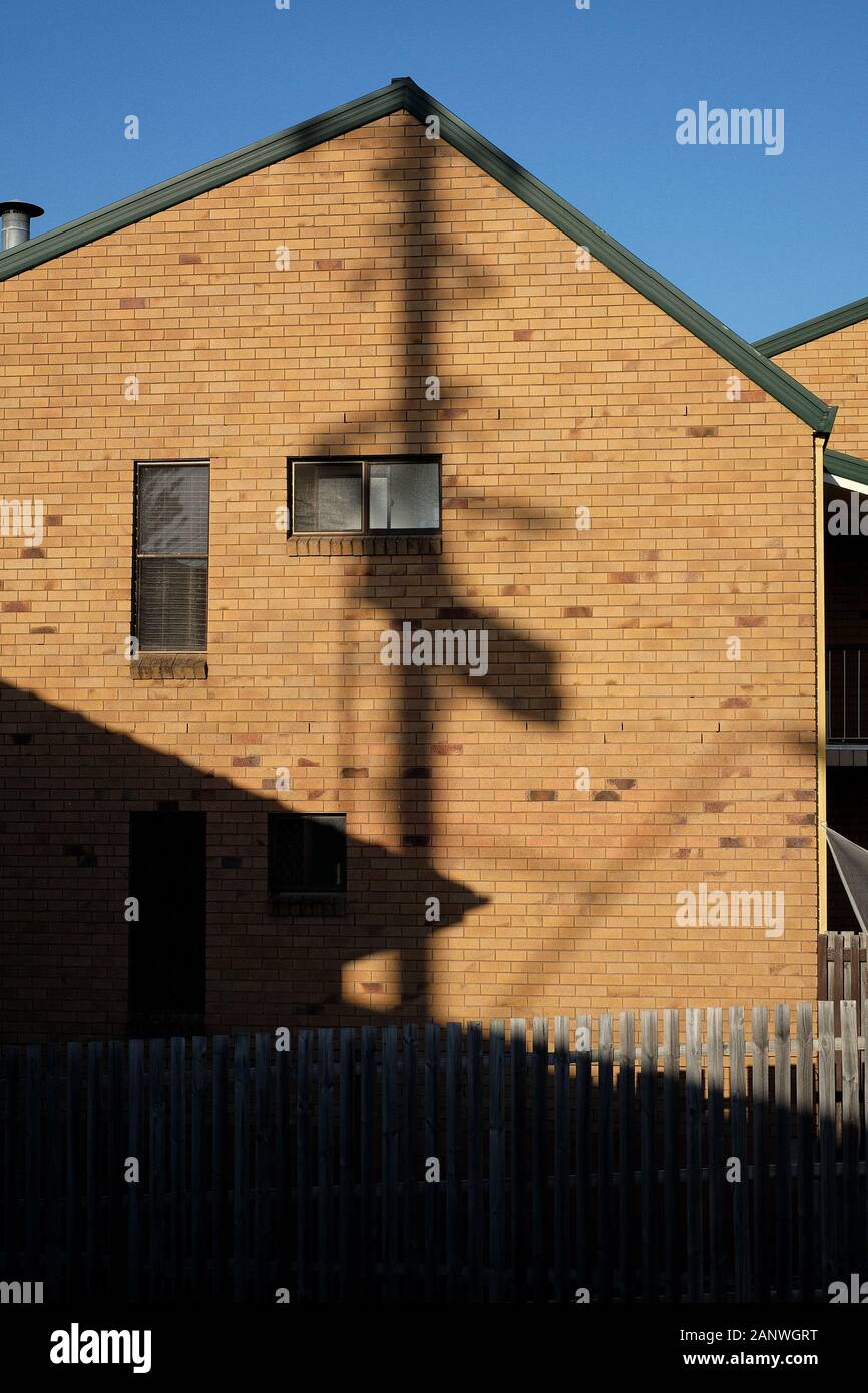 L'ombra di un polo di potenza cade a 90 gradi sulla parete di mattoni di fine due piani di una abitazione domestica a Carina Brisbane, come minimo come suona. Foto Stock