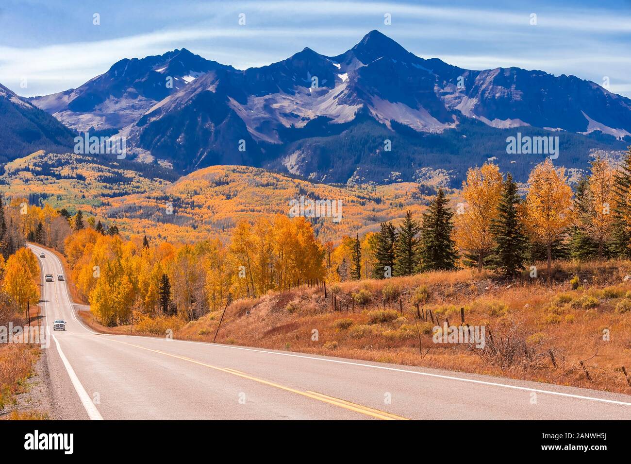 Veicoli viaggiano verso il basso Colorado Highway 145 nel mezzogiorno circondato da Autunno a colori nei pressi di Telluride, Colorado. Foto Stock